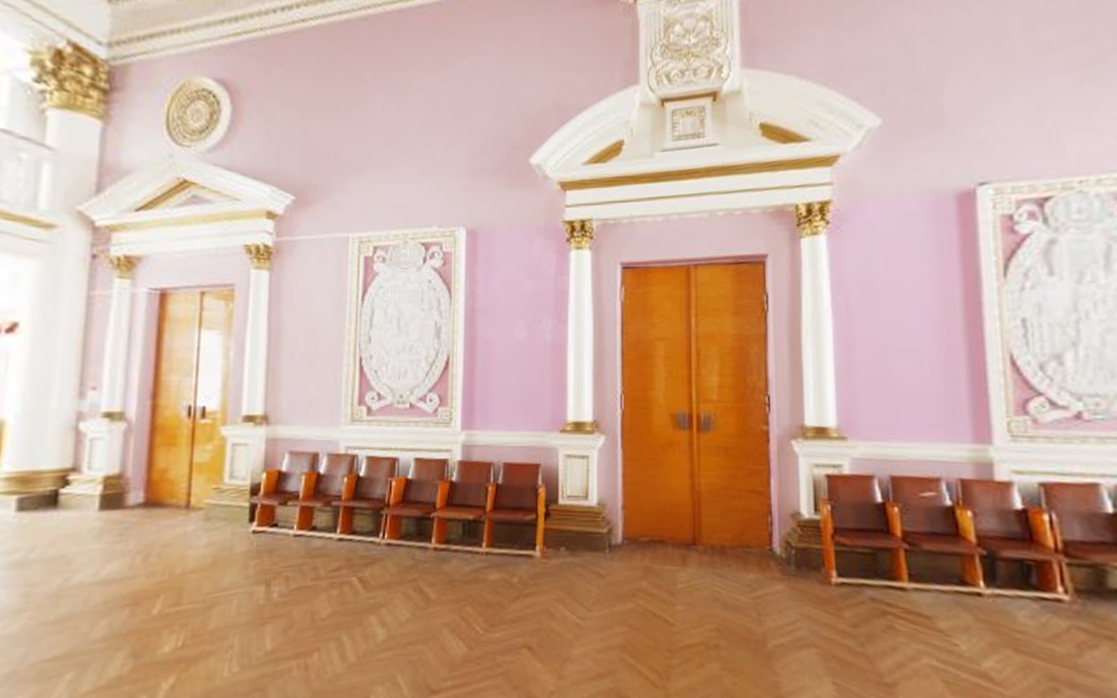 Pink-walled banquet hall with white columns, carved panels and wooden doors
